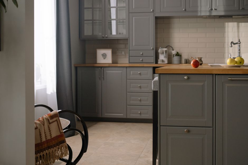 Stylish gray kitchen interior with wooden countertops, natural lighting, and modern design elements.
